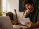 Independent musician reviewing an artist biography at a home studio desk