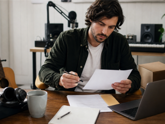 Independent musician reviewing business paperwork in a home studio