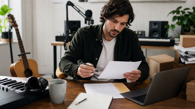 Independent musician reviewing business paperwork in a home studio