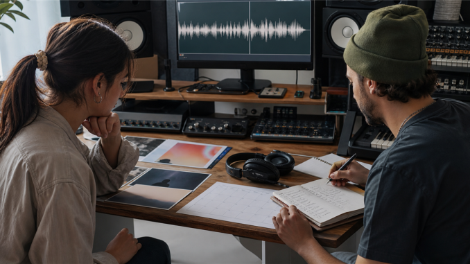 Musician and producer reviewing release materials and audio in a studio