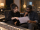 An independent musician and recording engineer compare a session plan inside a professional recording studio control room.