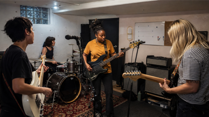 Four-piece independent band rehearsing together in a practice room