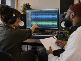 A musician and producer compare two reference songs against notes for an original recording in a project studio.