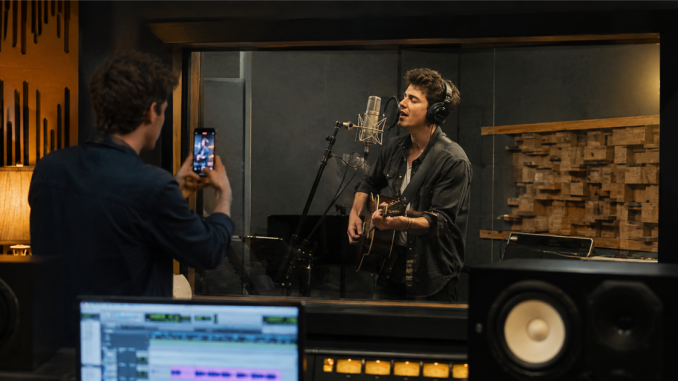 Singer recording while a collaborator documents the studio session