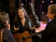 Guitarist speaking naturally with listeners beside a small venue stage